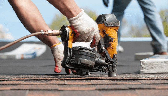 Up close view of roofer using drill tool for roof installation